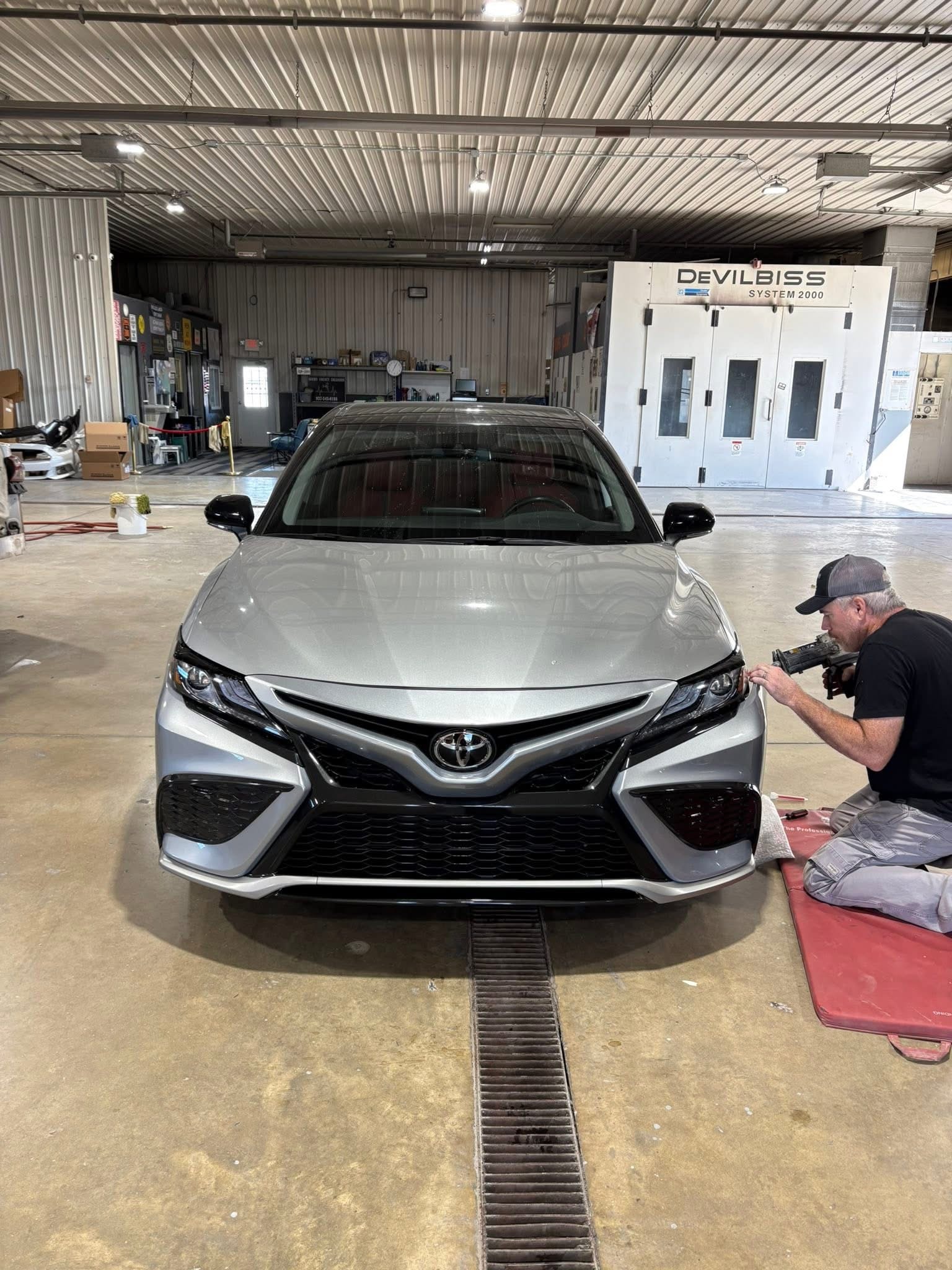 Technician photographing a silver Toyota during the collision repair assessment process